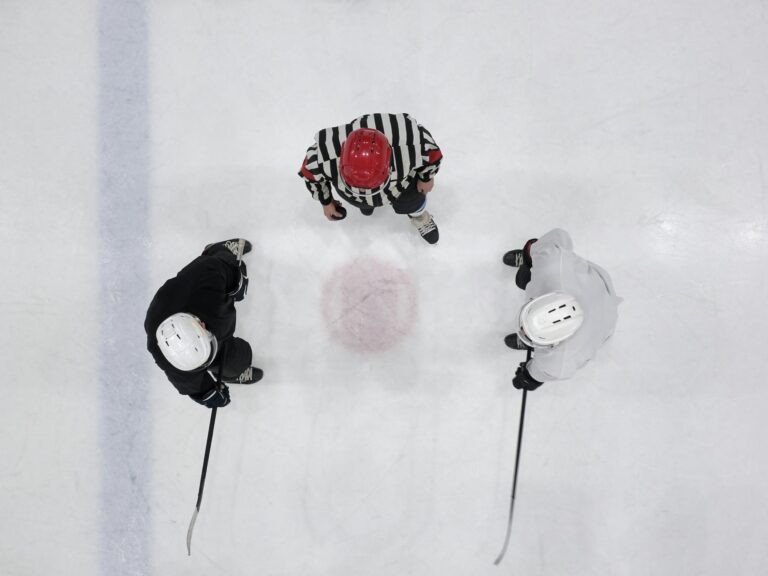 Overhead shot of ice hockey players and referee gathering on the rink for a face-off.